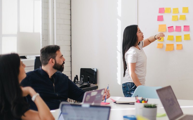 person puts post it in on wall in meeting