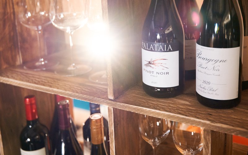a collection of wine glasses and bottles of wine on a shelf